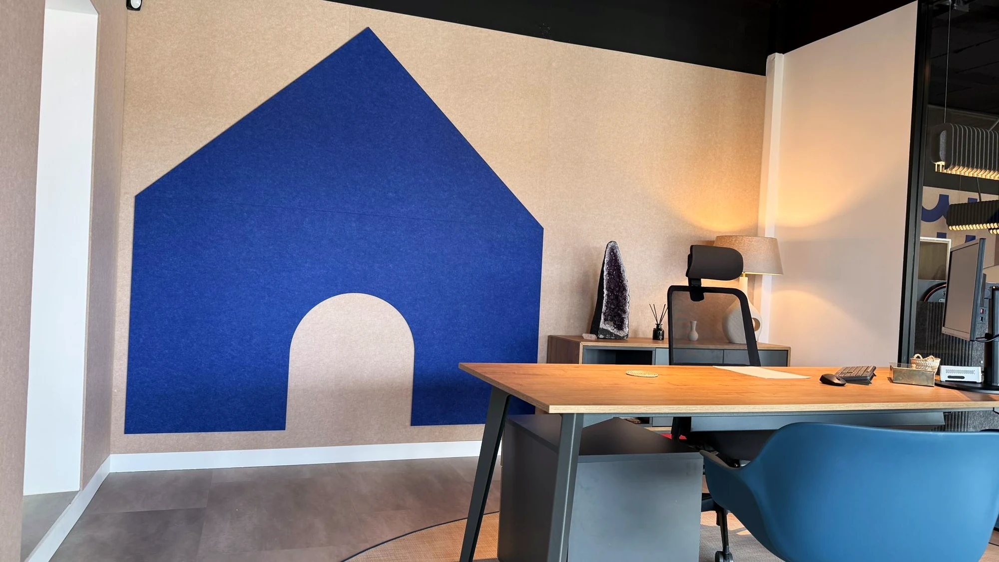 Silueta libre recortada en PET azul sobre un revestimiento acústico de pared