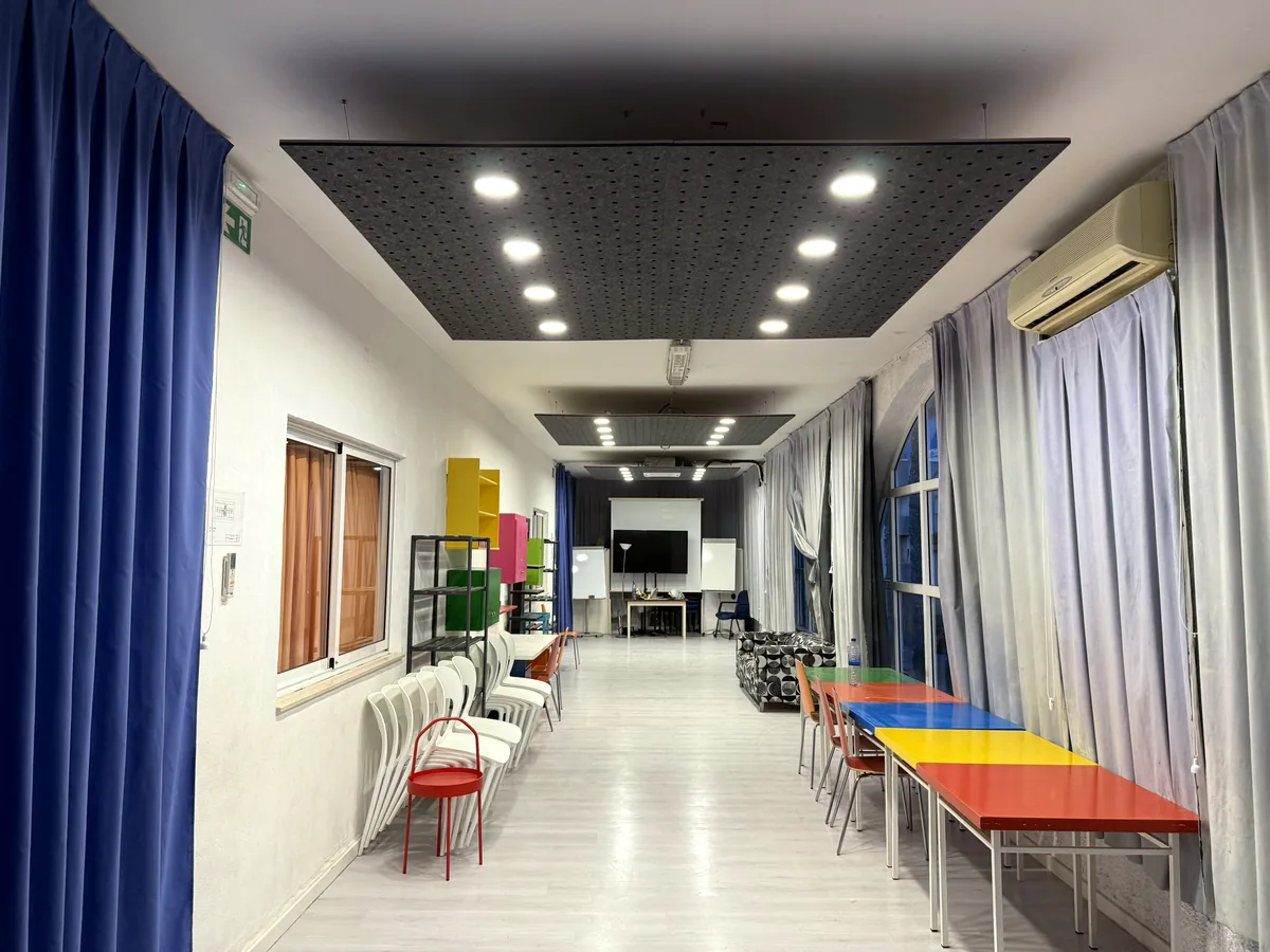 Sala polivalente con placa acústica negra suspendida en el techo