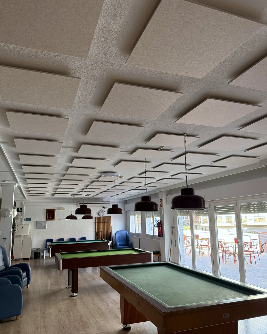 Sala de juegos con mesas de billar bajo un techo de placas acústicas suspendidas