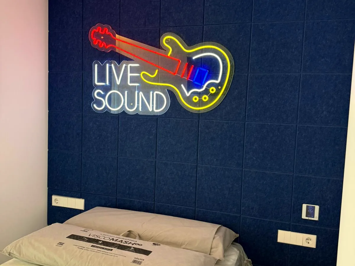 Sala de música con pared acústica azul y rótulo luminoso