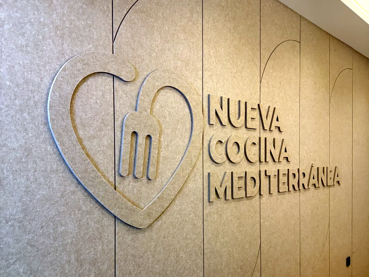 Logotipo cortado en V en un panel acústico de pared