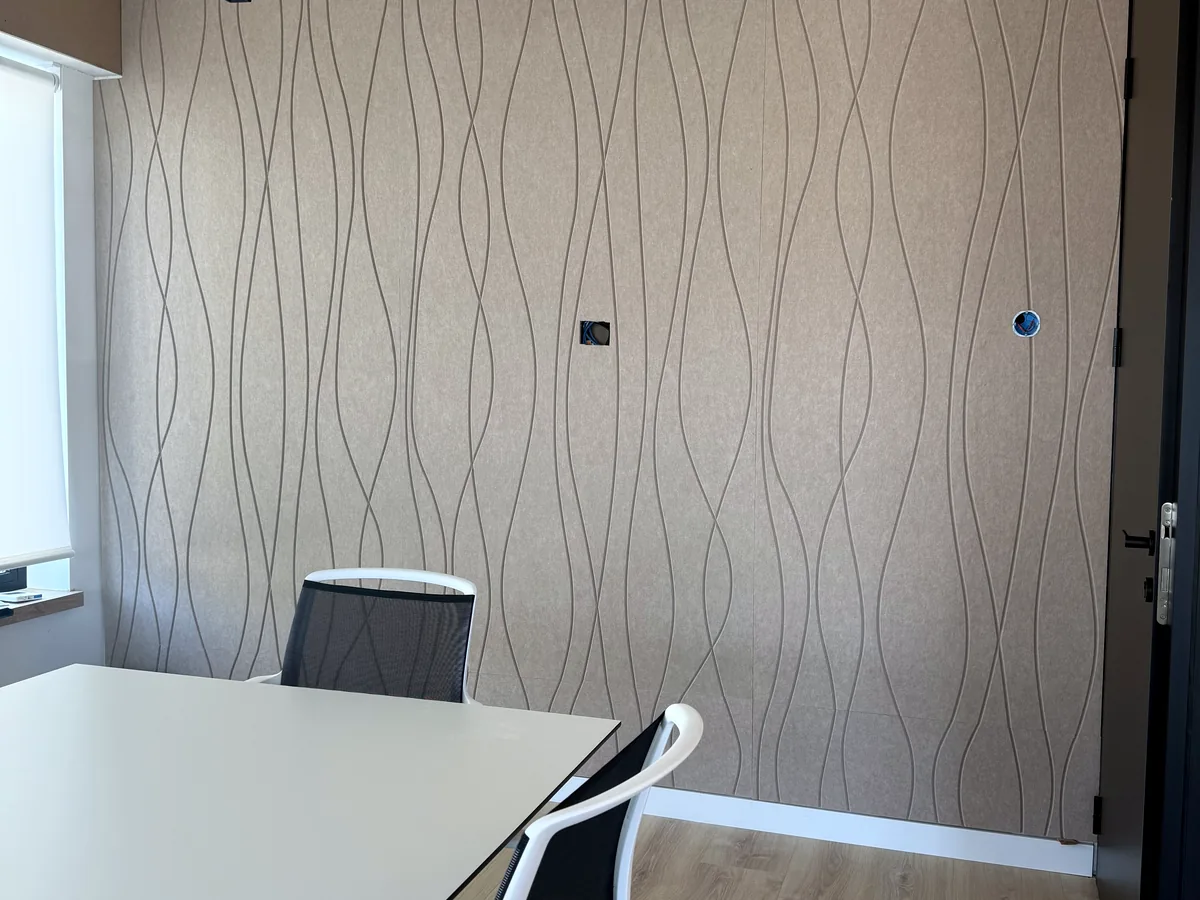 Pared acústica con líneas onduladas cortadas en V en una sala de reuniones