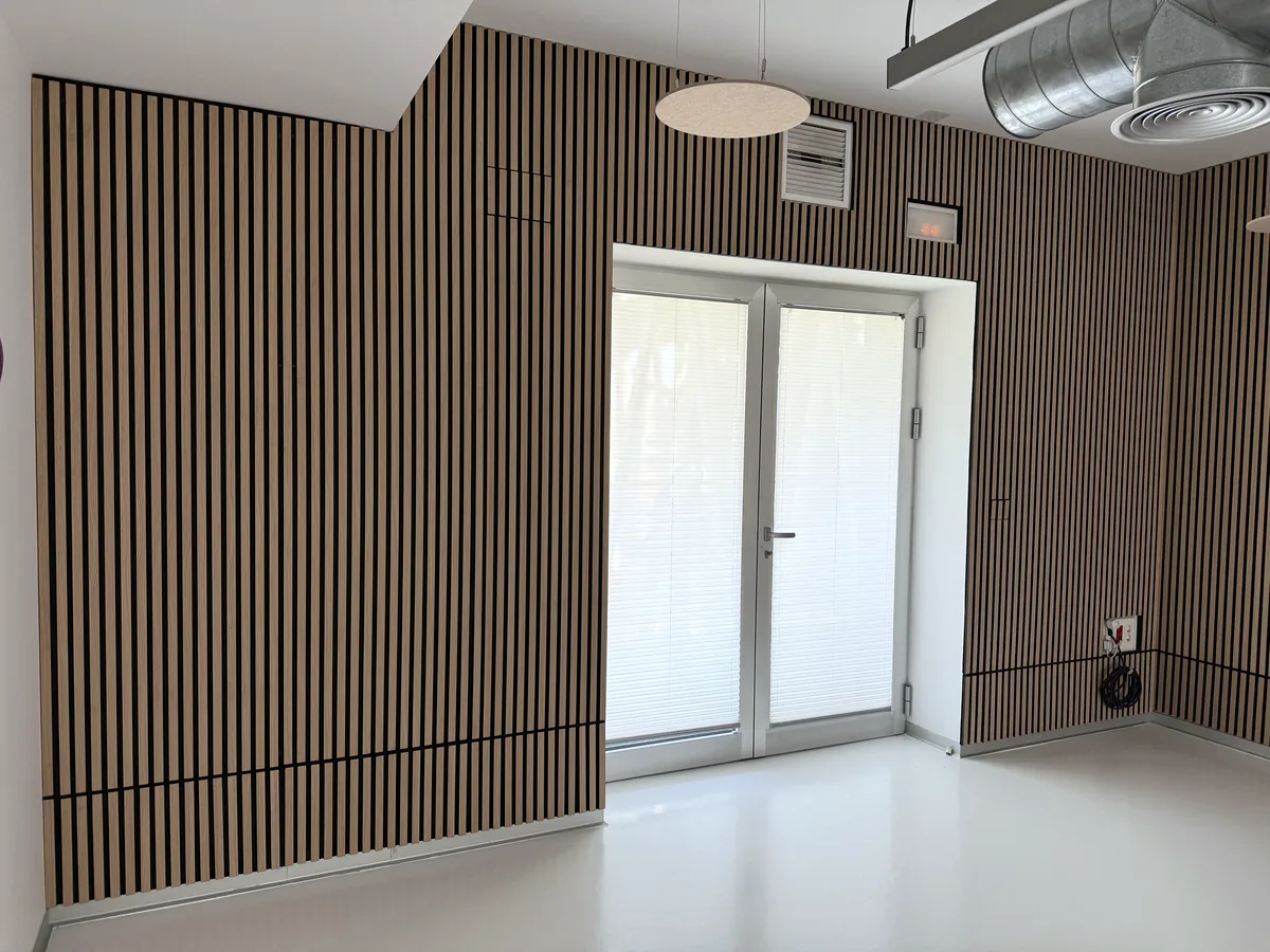 Revestimiento de listones de madera sobre panel VIVA en una sala con puerta acristalada