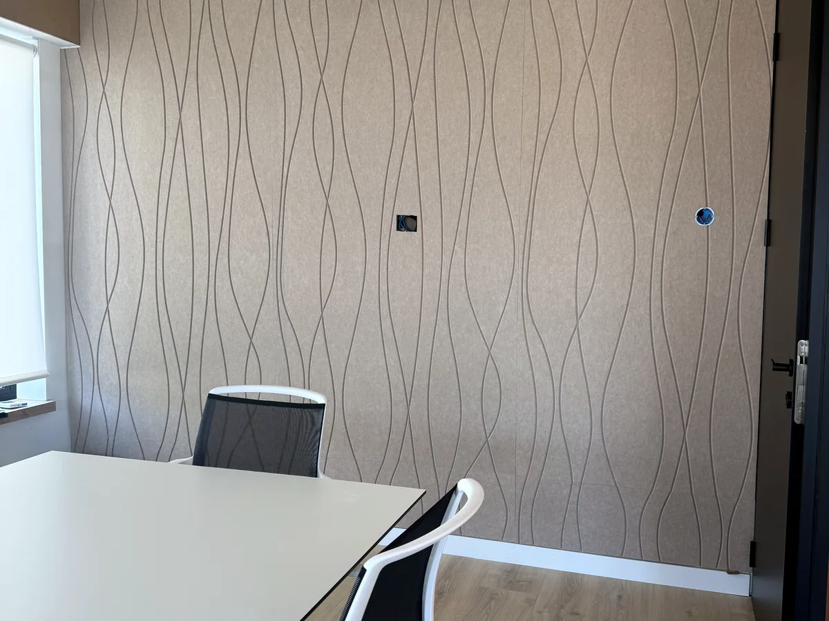 Sala de reuniones con panel acústico VIVA V CUT de líneas onduladas en la pared