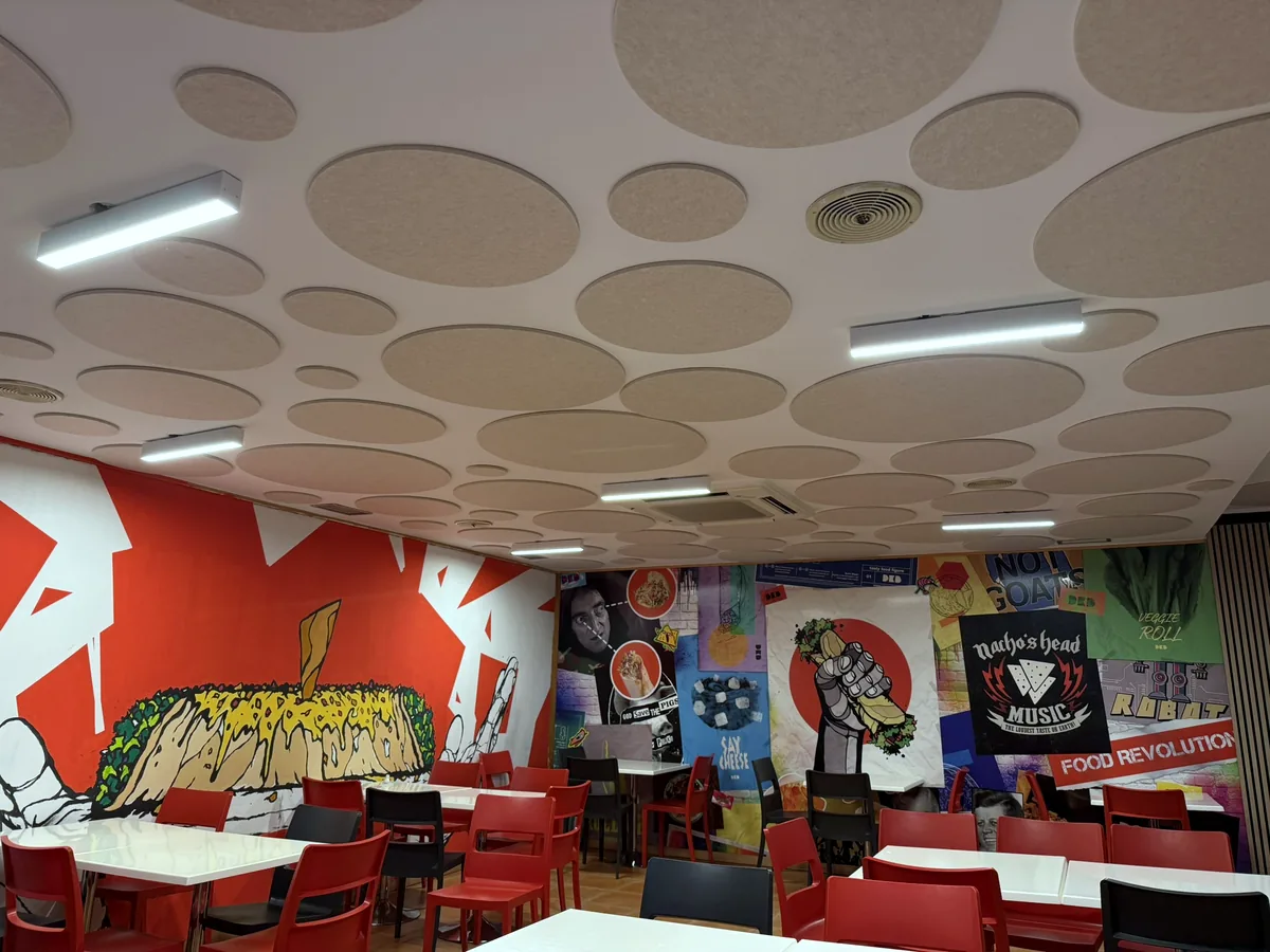 Comedor con discos acústicos VIVA en el techo y mural de colores