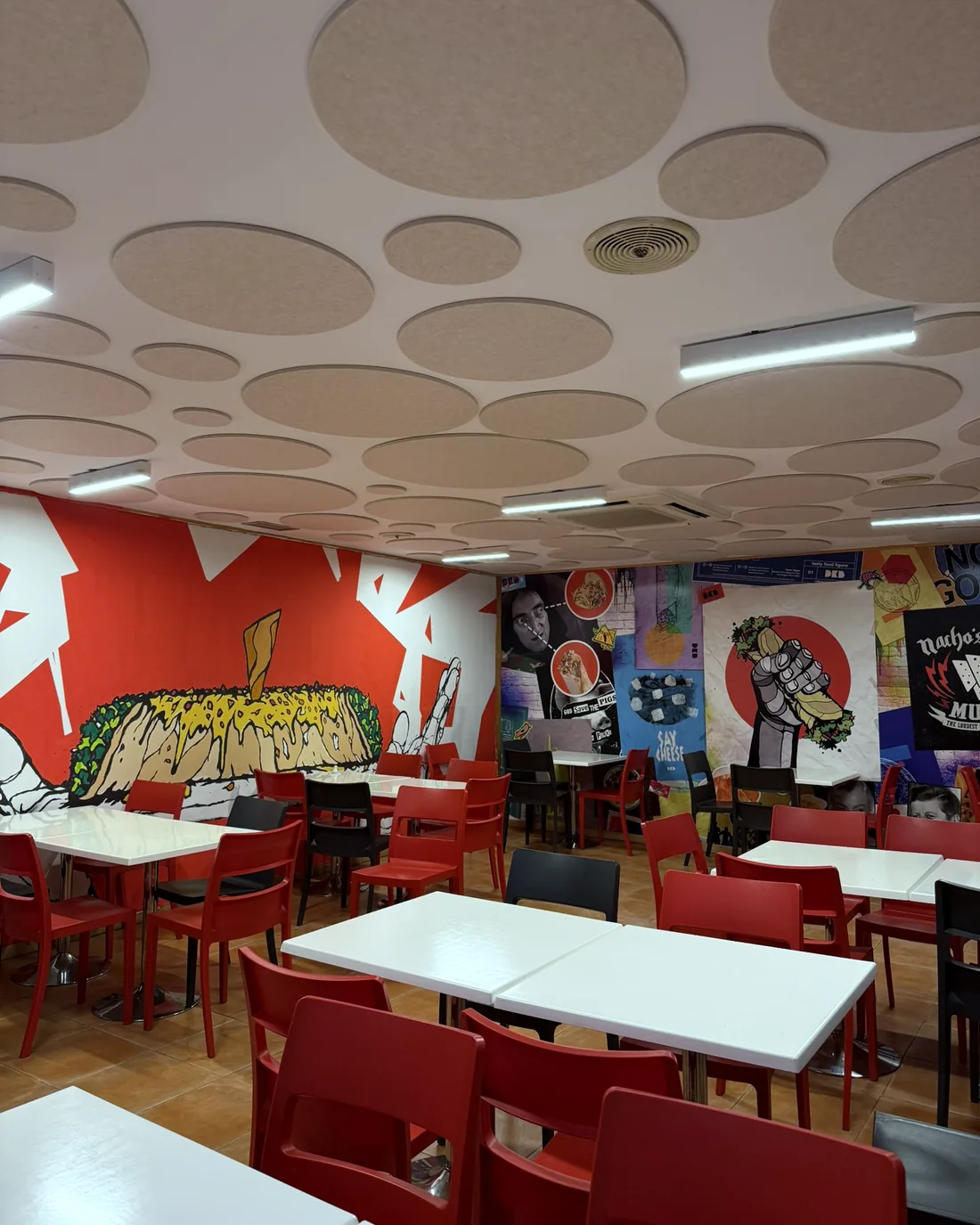 Comedor con sillas rojas bajo un techo de discos acústicos VIVA