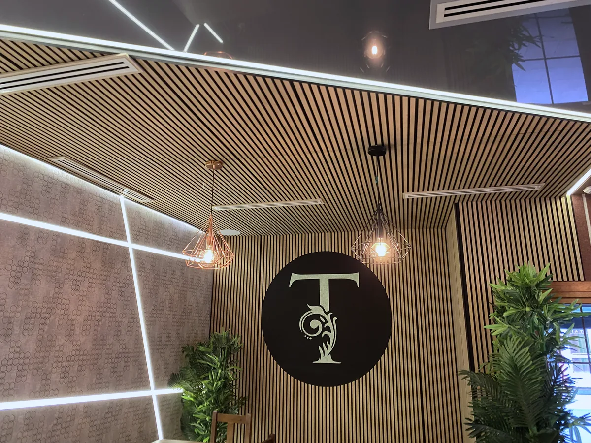 Restaurante con techo y pared de lamas acústicas y rótulo iluminado