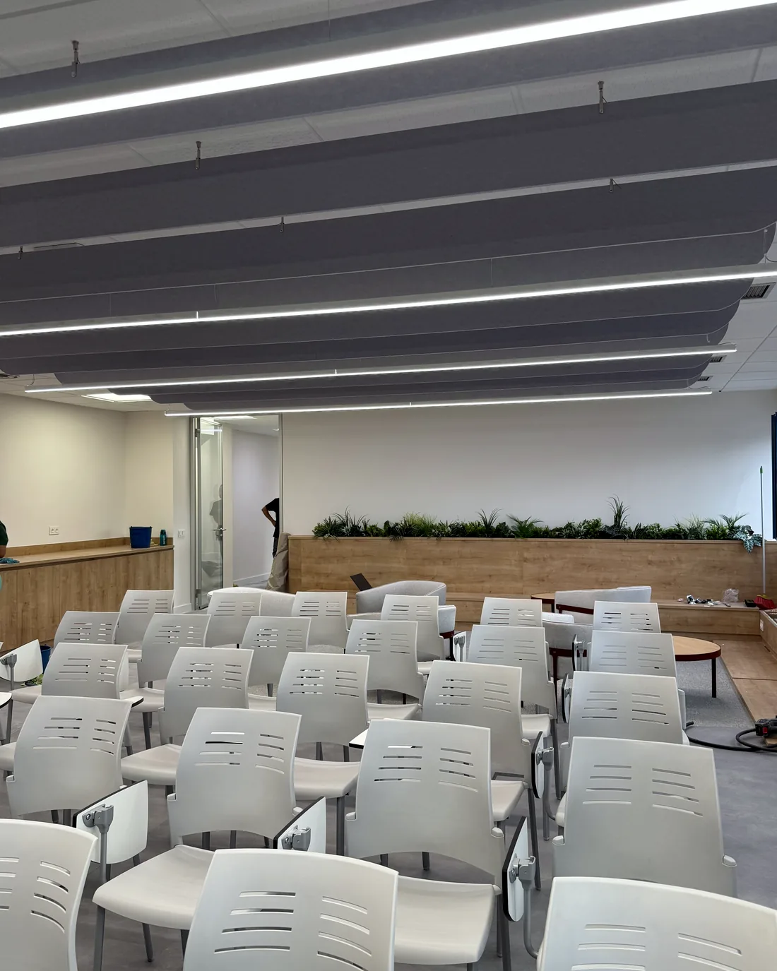 Sala de formación con baffles acústicos lineales suspendidos sobre las sillas
