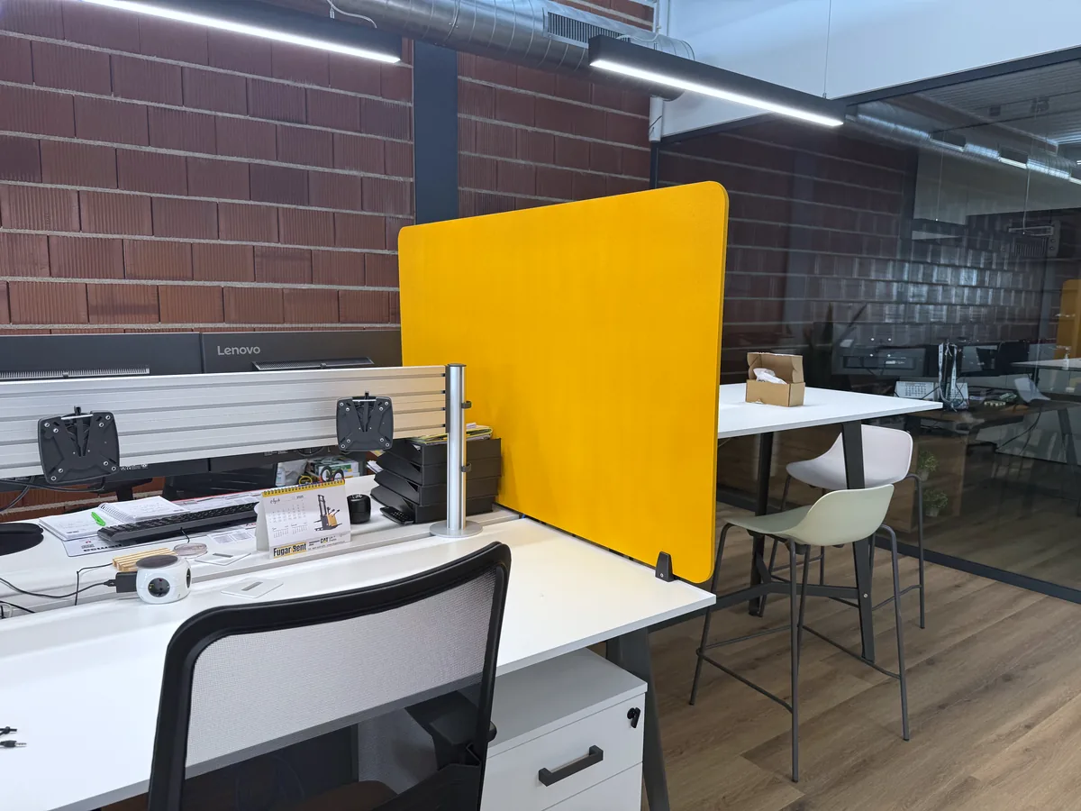 Separador acústico amarillo entre dos puestos de trabajo en una oficina