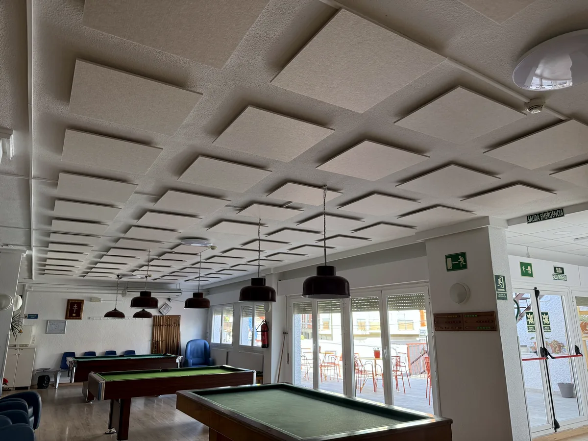 Techo de placas acústicas suspendidas en retícula sobre una sala de juegos